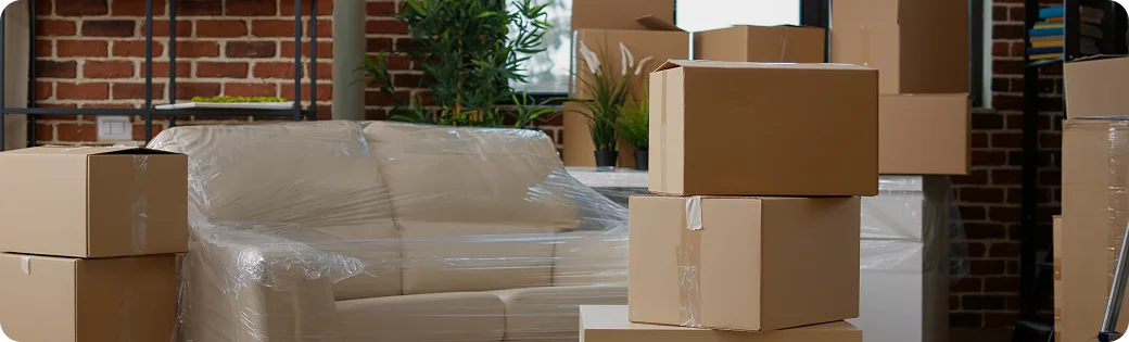 Une pièce remplie de cartons emballés et d'un canapé prêt à être déballé — symbole d'une nouvelle étape et d'un déménagement facile grâce à notre service.