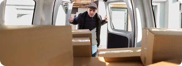 Un homme évalue une voiture chargée de cartons avant de commencer un déménagement organisé et sécurisé.