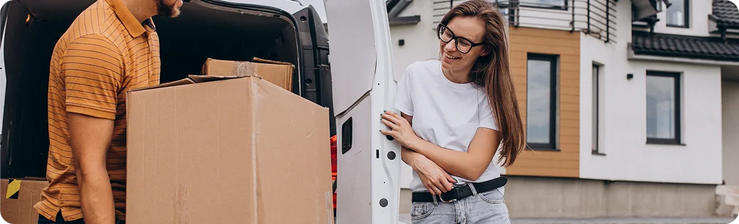 Un homme décharge des cartons dans une voiture, à côté de lui se tient une femme souriante — symbole d'un déménagement harmonieux et sans souci grâce à notre aide.